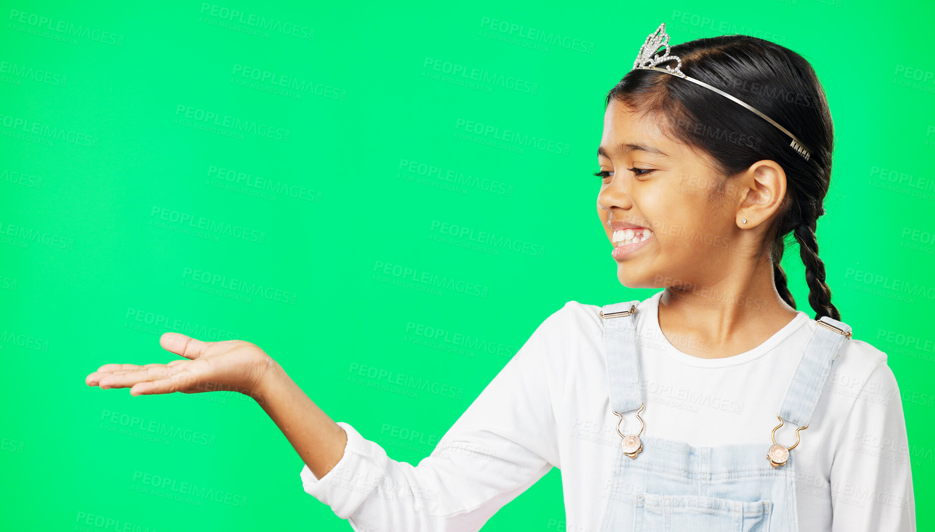 Buy stock photo Child, princess and green screen by hand for display of show, mockup and advertising in studio. Happy little girl, tiara and smile for presenting for marketing, open palm and empty space background