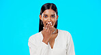 Woman, surprise and face with hand on mouth for comic story, secret or laugh for funny gossip by blue background. Young, gen z model and indian girl with laughing, amazed and wow for news in portrait