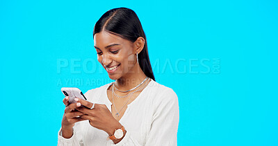 Phone, typing and young woman isolated on blue background for social media post, networking and chat tech. Happy indian person or online user with mobile app, smartphone or cellphone in studio mockup