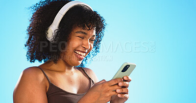 Black woman, phone and headphones isolated on blue background listening to music, social media video or funny meme. Happy gen z person laughing for audio tech, internet post and cellphone in studio