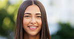 Portrait of a beautiful girl standing and commuting in the city. One happy and stylish young female smiling and relaxing downtown. Trendy young woman showing her teeth, laughing and traveling in town