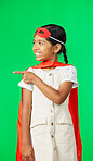 Face, superhero costume and girl pointing on green screen in studio isolated on a background. Smile, cosplay character and happy child or kid in cape point to mockup, product placement or marketing.