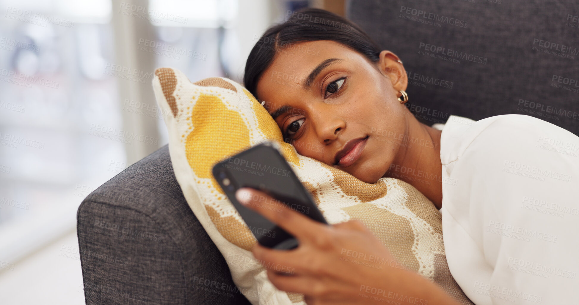 Buy stock photo Social media, online and Indian woman on sofa with phone reading website, internet and text message at home. Communication, connection and person laying in living room on smartphone for mobile app