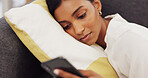 Girl on sofa typing on a phone in living room. Social media, technology and communication, a happy young woman lying on a couch and chatting to friends online or watching a funny video.