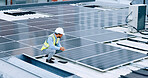 Engineer or contractor measuring solar panels on a roof of a building. Engineering technician or electrician installing alternative clean energy equipment and holding a tablet to record measurements