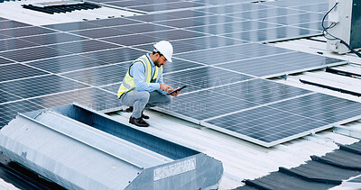 Engineer or contractor measuring solar panels on a roof of a building. Engineering technician or electrician installing alternative clean energy equipment and holding a tablet to record measurements