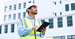 Male engineer checking data on digital tablet and inspecting construction site. Technician in a hardhat doing management and project planning outdoors. Skilled worker looking or overseeing operations