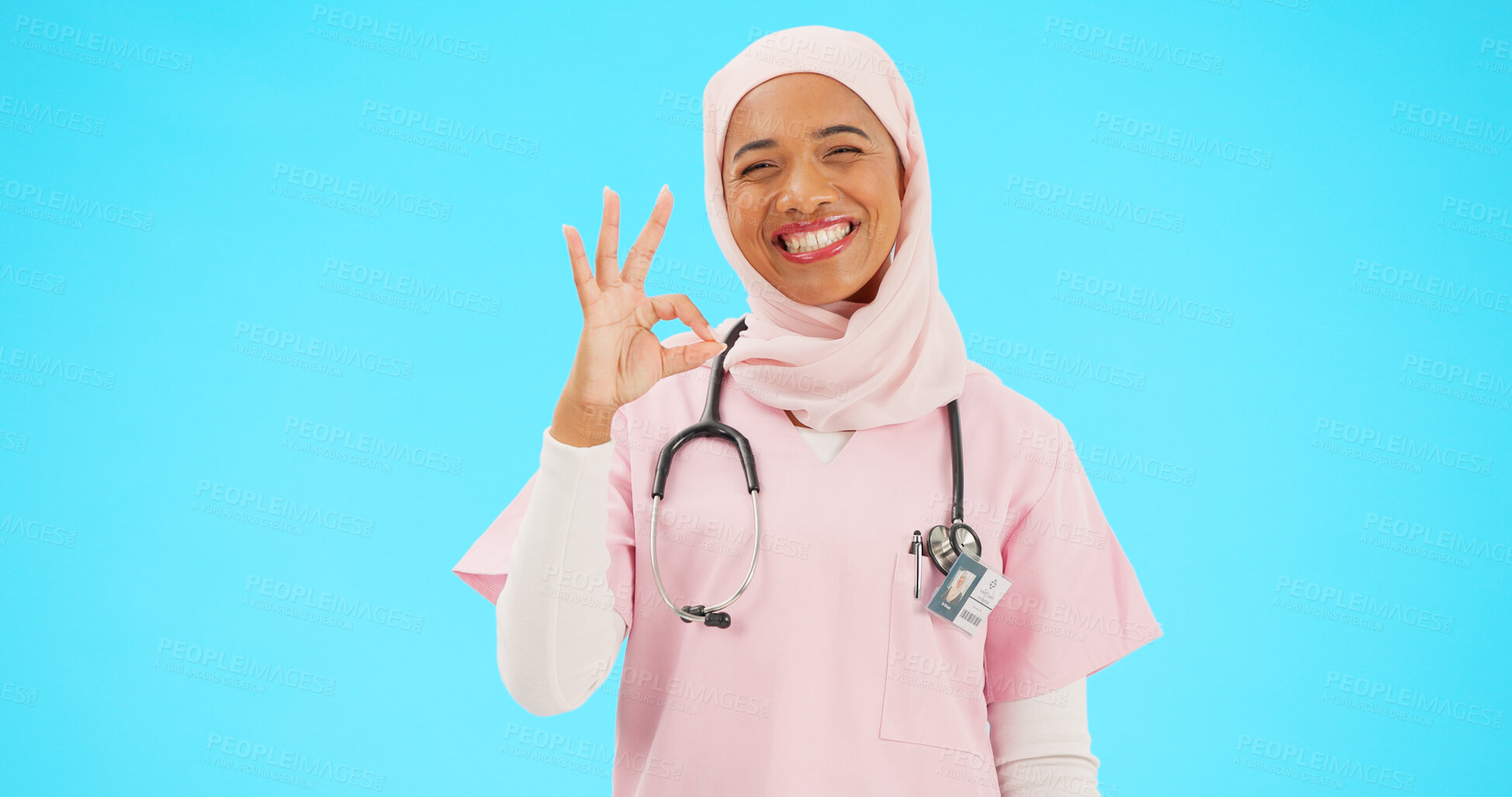Buy stock photo Muslim woman, ok sign and doctor in studio portrait, review and good service by blue background. Islamic person, nurse and hijab with emoji, happy and agreement with choice, feedback and healthcare