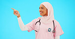 Face, nurse and Muslim woman pointing to mockup in studio isolated on a blue background. Portrait, healthcare professional and happy Islamic person with marketing, advertising or product placement.