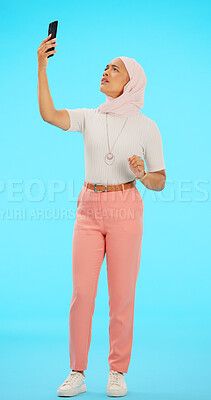 Buy stock photo Muslim woman, selfie glitch or connectivity problem with advertising, pose and hijab with casual clothes. Islamic female, model and scarf in annoyed with gen z aesthetic or blue studio background