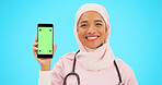 Green screen, phone and nurse isolated on blue background with medical mobile app, tracking marker and healthcare mockup. Happy islamic doctor or woman face with cellphone product placement in studio