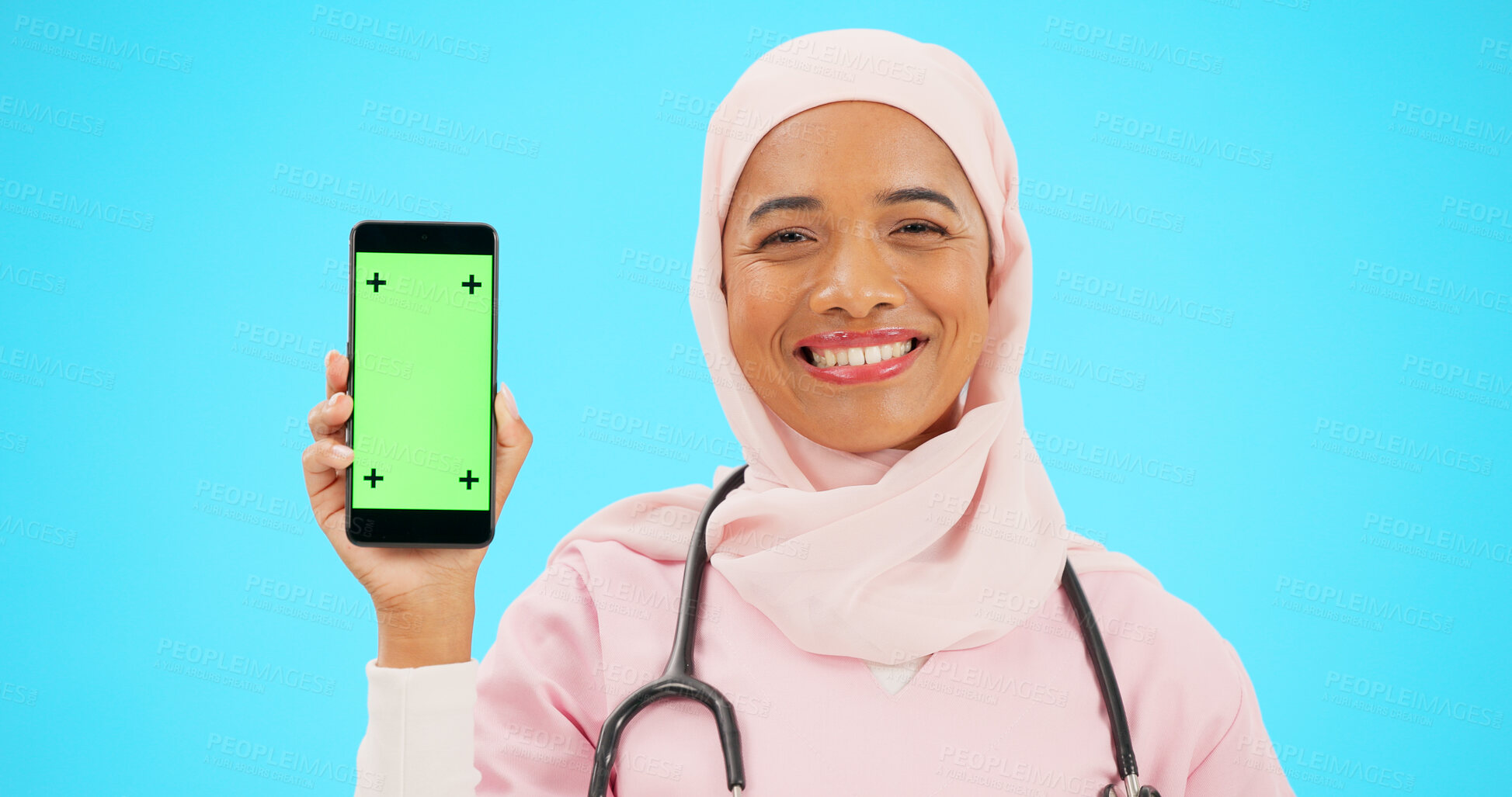 Buy stock photo Phone, doctor and Islam woman with green screen in studio for healthcare, medicine and mockup space. Happy, nurse and portrait of person with smartphone for telehealth mobile app on blue background