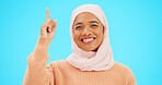 Happy muslim, woman and pointing finger portrait with space for mockup, advertising or promotion. Islamic female with hand, smile and hijab for announcement, Allah or God and sale on blue background