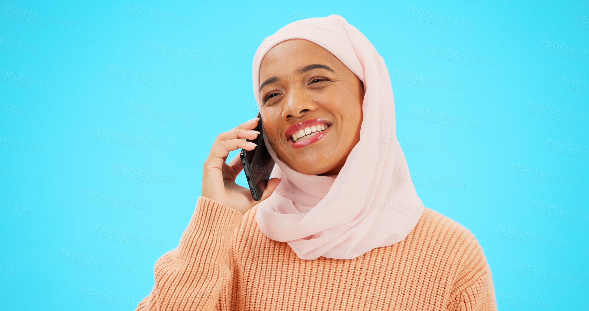 Buy stock photo Islamic woman, phone call and smile in studio with thinking, chat and contact by blue background. Muslim person, smartphone and listening for happy conversation, ideas and talk on mobile network