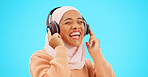 Happy woman, headphones and dancing isolated on blue background listening to music for celebration and singing . Funny, dance and muslim, gen z or hijab person with streaming technology in studio