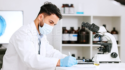 Scientist and research or medical engineer doing experiments to create a cure in a lab while wearing a mask. Healthcare professional working with science equipment and writing notes in a laboratory