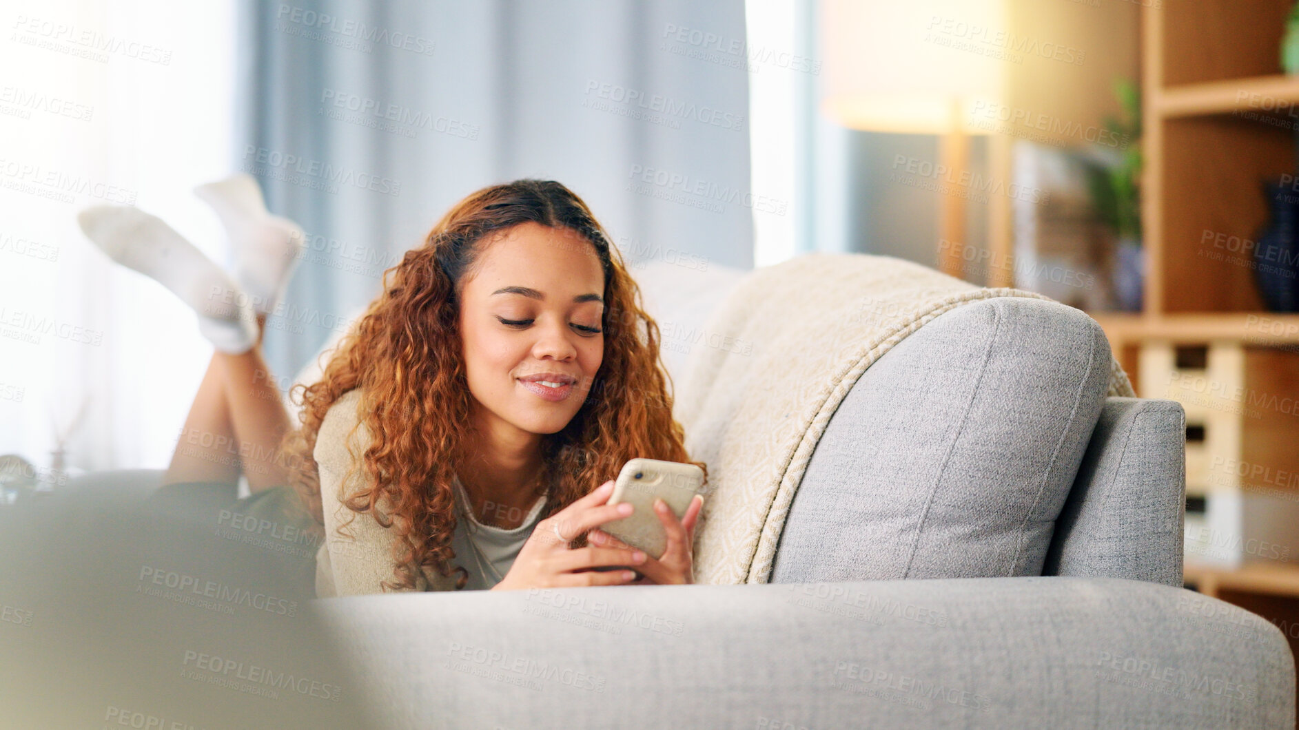 Buy stock photo Woman, smile and typing on a phone for connection, a meme or social media at home. Happy, young girl and reading a chat, online conversation or on a mobile app to relax on the living room sofa