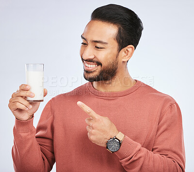 Buy stock photo Man pointing at milk, drink and health with nutrition, calcium and vitamins with vanilla shake isolated on studio background. Male person with smile, promote dairy product in glass and healthy life
