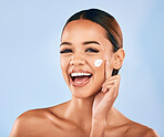 Happy woman, face and portrait with skincare cream for beauty moisturizer against a blue studio background. Female person or model with smile in happiness for facial lotion, cosmetics or products