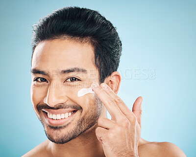 Buy stock photo Skincare, face cream and portrait of man in studio for  natural, wellness and health routine. Happy, cosmetic and male model with facial spf, lotion or sunscreen for dermatology by a blue background.