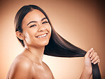 Woman, hair style and cosmetic in studio portrait for beauty, healthy shine and smile by brown background. Girl, youth model and haircare with cosmetics, hand and self care for aesthetic by backdrop