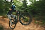 Extreme sports, trail and athlete doing a trick on a bike while riding for competition practice in the woods. Fitness, blur motion and male biker with skill training or exercise in an outdoor forest.