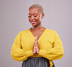 Hands together, smile and black woman with prayer, hope and religious belief against a grey studio background. Female person, worship and model with hand gesture, happiness and faith with wellness