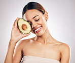 Happy, skincare and woman with avocado in studio for natural, cosmetics or  facial on grey background. Smile, glow and girl model with fruit for vegan, environmental or skin detox with collagen 
