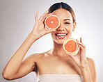 Portrait, skincare and happy woman with grapefruit in studio fo organic, cosmetic or treatment on grey background. Citrus, face and female model with fruit for eco, vegan or skin detox with vitamin c