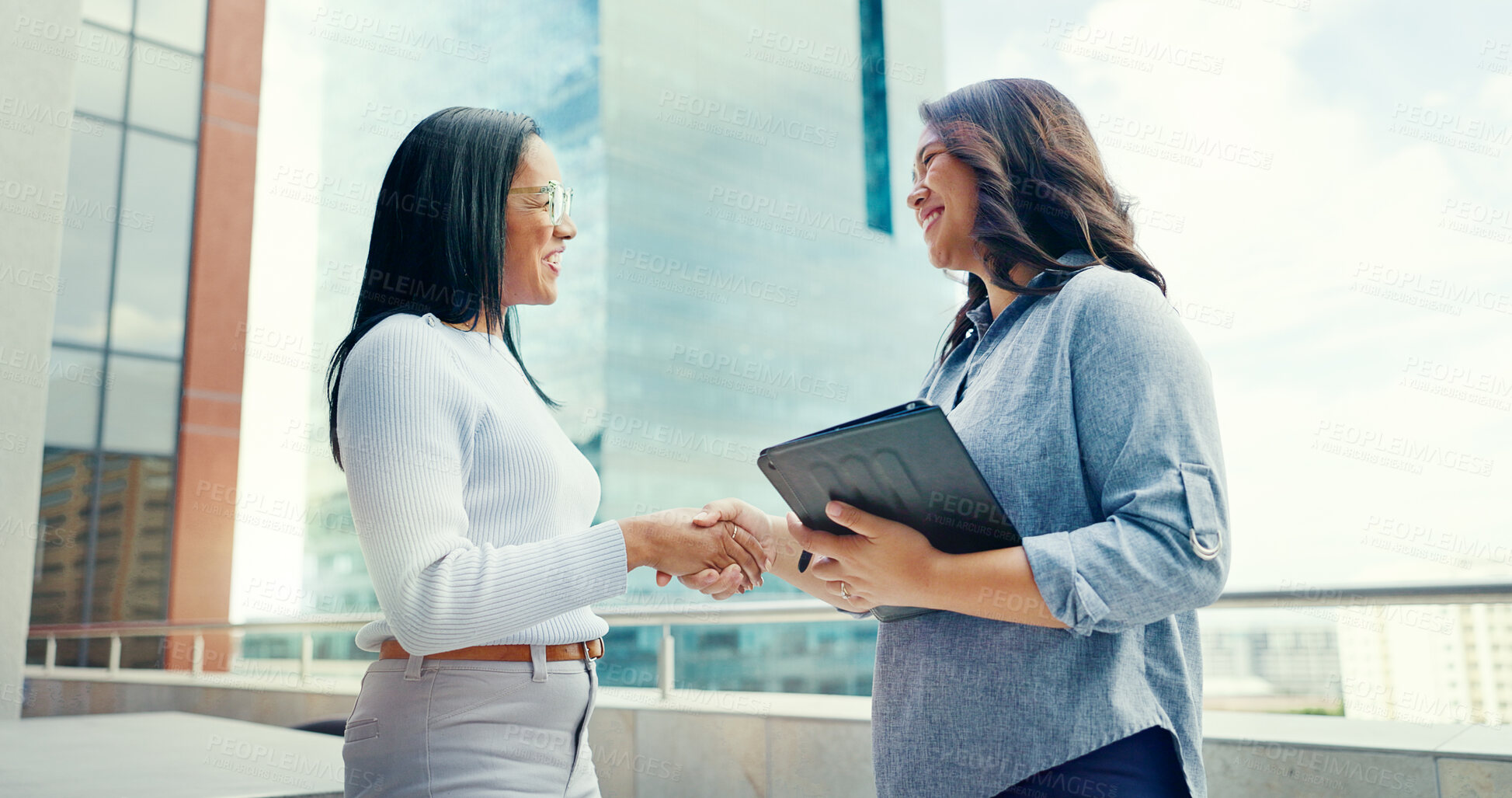 Buy stock photo Tablet, handshake and business women on rooftop of building in city for b2b deal or partnership. Digital technology, team and professional female shaking hands in agreement on office balcony in town.