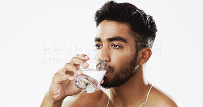 Man drinking water, hydration and health with serious face and glass in hand isolated on white background. Thirsty Indian male in studio, h2o and mineral with healthcare, wellness and mockup space