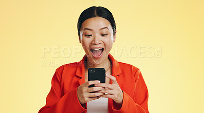 Winner, success celebration and Asian woman with phone in studio isolated on a yellow background. Surprise, fist pump or happy female with mobile to celebrate after winning lottery prize or good news
