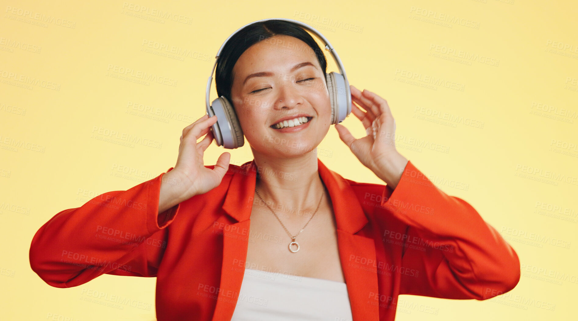 Buy stock photo Music, headphones and happy Asian woman listening to audio in studio isolated on a yellow background. Technology, sound and person streaming online, hearing radio and dancing to podcast for freedom