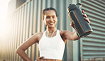 Closeup of one fit young hispanic woman holding a water bottle with the word "run" displayed in a digital time font while exercising in an urban setting outdoors. Female athlete taking a break to quench thirst and cool down after cardio training workout