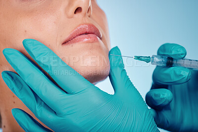 Buy stock photo Fillers, hands and cosmetic surgery with a woman and doctor in studio on a blue background for face change. Beauty, skin and injection with a surgeon holding a syringe for female client facial filler