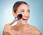 Woman, smile and makeup brush in studio for cosmetic self care, beauty or happy by blue background. Model, happiness and cosmetics brush and self love, skin wellness or foundation on face by backdrop