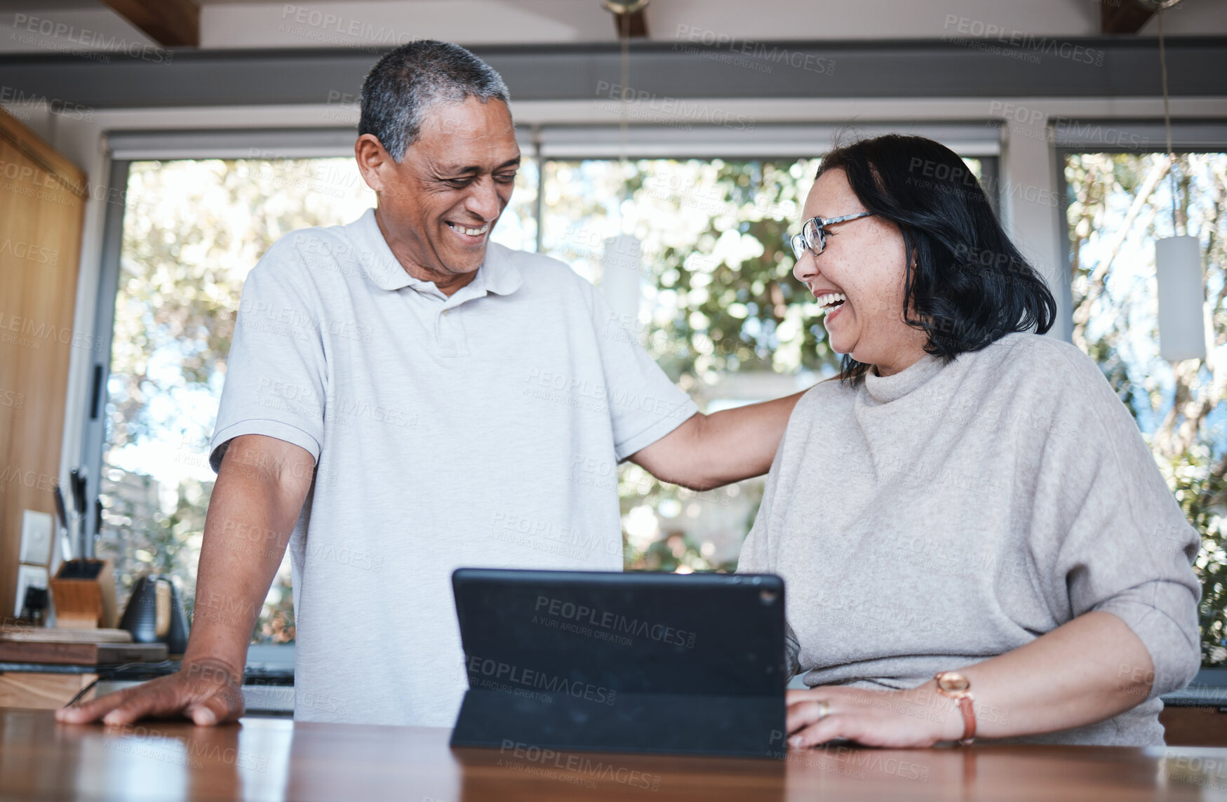 Buy stock photo Happy, laughing and senior couple with digital tablet in a kitchen, relax and bonding in their home. smile, laugh and old people enjoying retirement, joke and fun while browsing online in their house