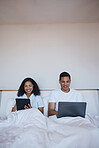 Technology, relax and couple in bed networking on social media or the internet together at home. Happy, smile and young man and woman browsing on a digital tablet and laptop in bedroom in the morning
