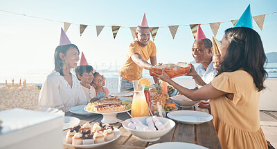 Buy stock photo Birthday, parents and children with food by beach for event, celebration and party outdoors. Family, social gathering and mother, father with kids at picnic with cake, presents and eating together