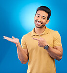 Portrait, man or palm for advertising space, mockup or product placement in studio, blue background or promotion deal. Happy asian, male model and pointing to presentation, information or news review