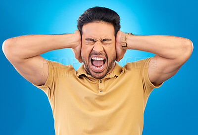 Buy stock photo Man covering his ears while screaming in a studio for angry, upset or mad argument expression. Crazy, shout and young male person with an open mouth for loud voice gesture isolated by blue background