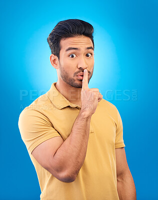 Buy stock photo Man, studio portrait and secret with finger on lips for silence, quiet and stop noise by blue background. Young asian guy, student and icon to cover mouth for deal, confidential and privacy emoji