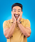 Happy, excited man and surprise portrait in studio with Asian model with teeth and joy. Blue background, male person and casual fashion with handsome and friendly guy with modern style and wow face
