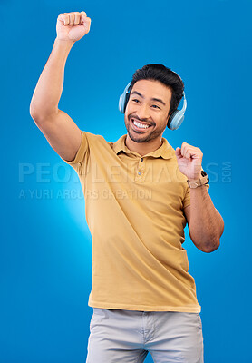 Buy stock photo Happy, music and dancing with headphones or asian man in blue background for entertainment. Energy, guy and song with earphone with happiness for streaming online with radio with tech in studio.