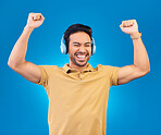 Headphones, success and man, winner or student excited for results, news or music, yes or energy. Happy, freedom and asian person listening to audio, podcast and celebration on studio blue background