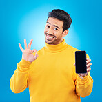 Advertising, portrait of a man with smartphone and okay sign in blue background happy for social networking. Online communication or technology, marketing or branding and male person with cellphone