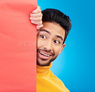Buy stock photo Surprise, peeking and young man in studio with a wow, omg or wtf facial expression by a board with mockup. Happy, shock and male model with sneaky face by poster with mock up space by blue background