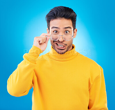 Buy stock photo Portrait, glasses and funny face with a man on a blue background in studio for vision or comedy. Comic, humor and fashion with a silly male person joking in prescription frame lenses or eyewear