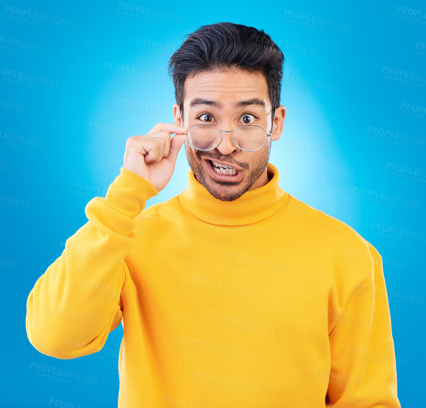 Buy stock photo Portrait, glasses and funny face with a man on a blue background in studio for vision or comedy. Comic, humor and fashion with a silly male person joking in prescription frame lenses or eyewear