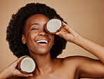 Happy, glow and black woman with coconut for skincare, dermatology treatment and health. Laughing, wellness and an African model with a smile for food for hair care isolated on a studio background
